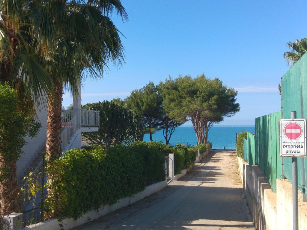 an empty street with palm trees and the ocean at Villa Sara Timpi Russi in Sciacca
