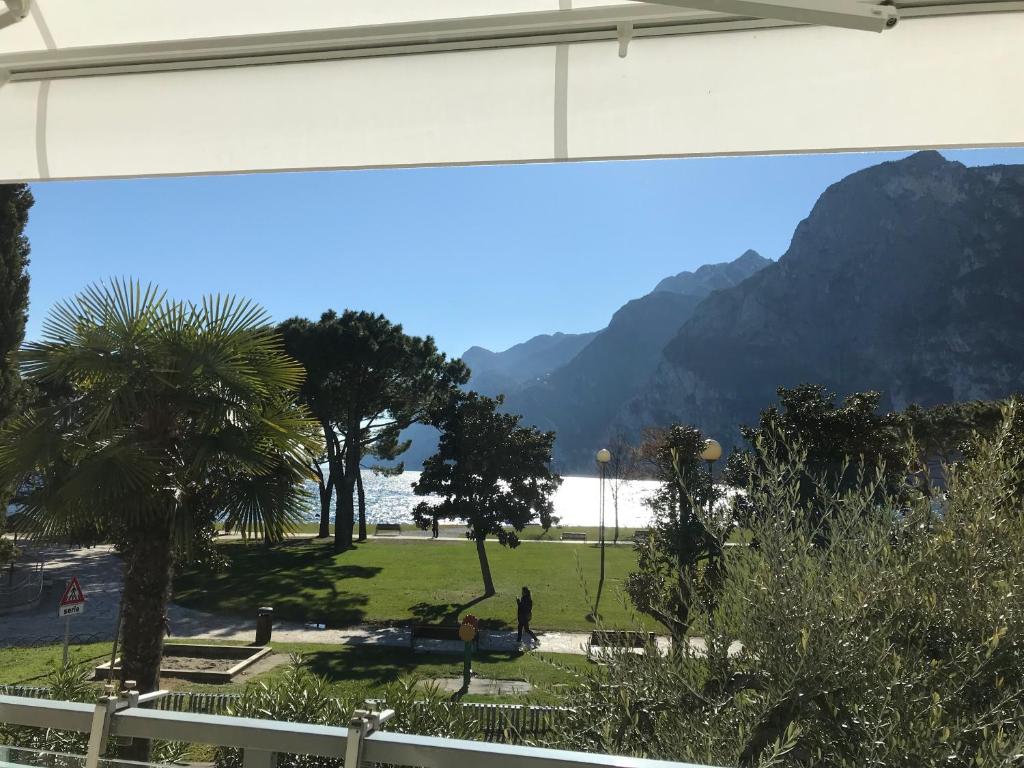 a view of a park with palm trees and mountains at Appartement Lago Blu in Riva del Garda