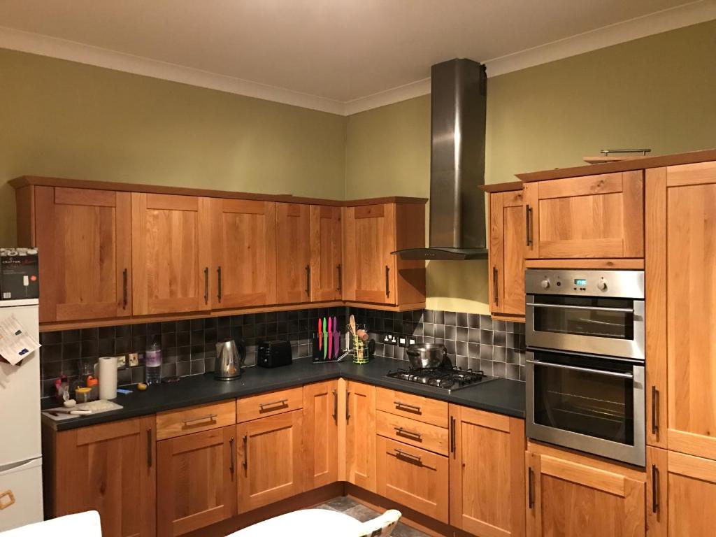 a kitchen with wooden cabinets and black counter tops at Oban Town Centre Apartment in Oban