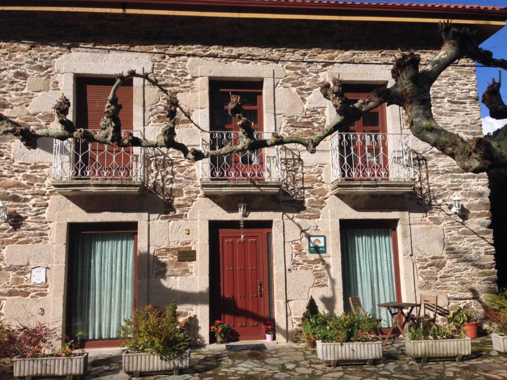 un edificio de piedra con puerta roja y ventanas en Casa Alpargateiro en Os Peares