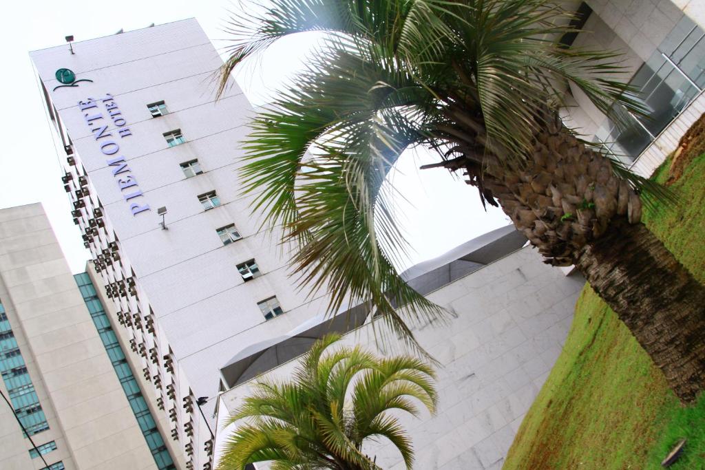 a tall building with palm trees in front of it at Piemonte Hotel in Nova Lima