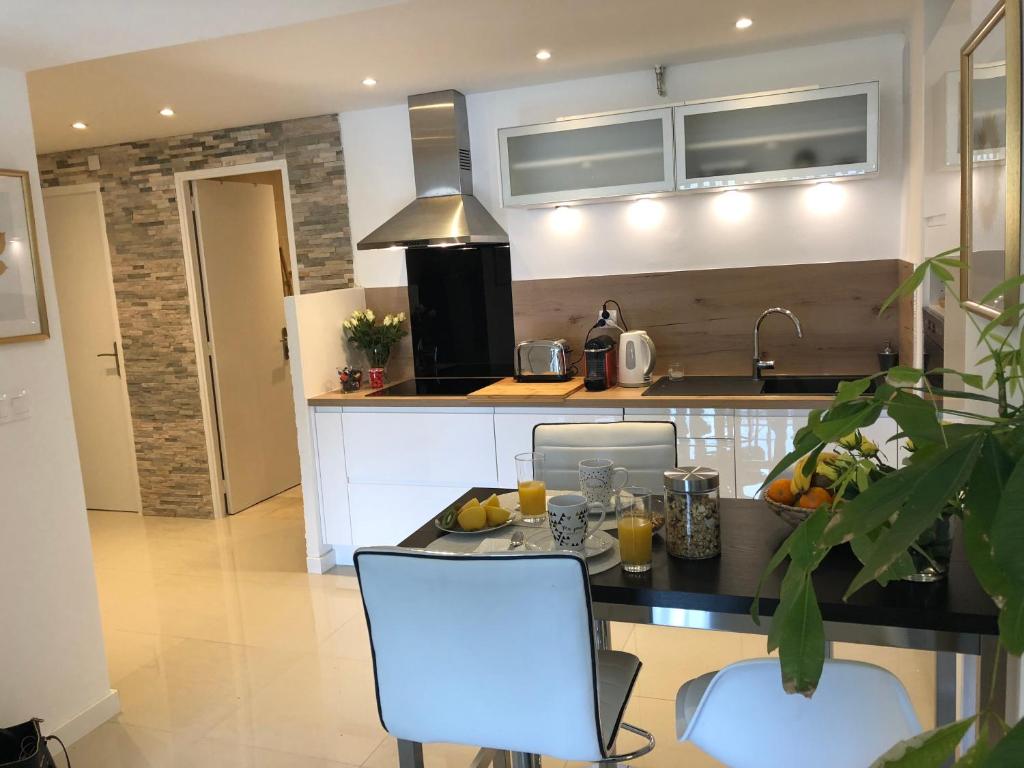 a kitchen with a table and two white chairs at Appartement Cosy Calme Central-Terrasse Proche Palais in Cannes