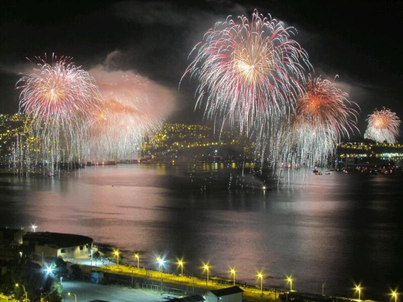 un espectáculo de fuegos artificiales sobre un cuerpo de agua en Edificio Los Navegantes, Valparaiso, en Valparaíso