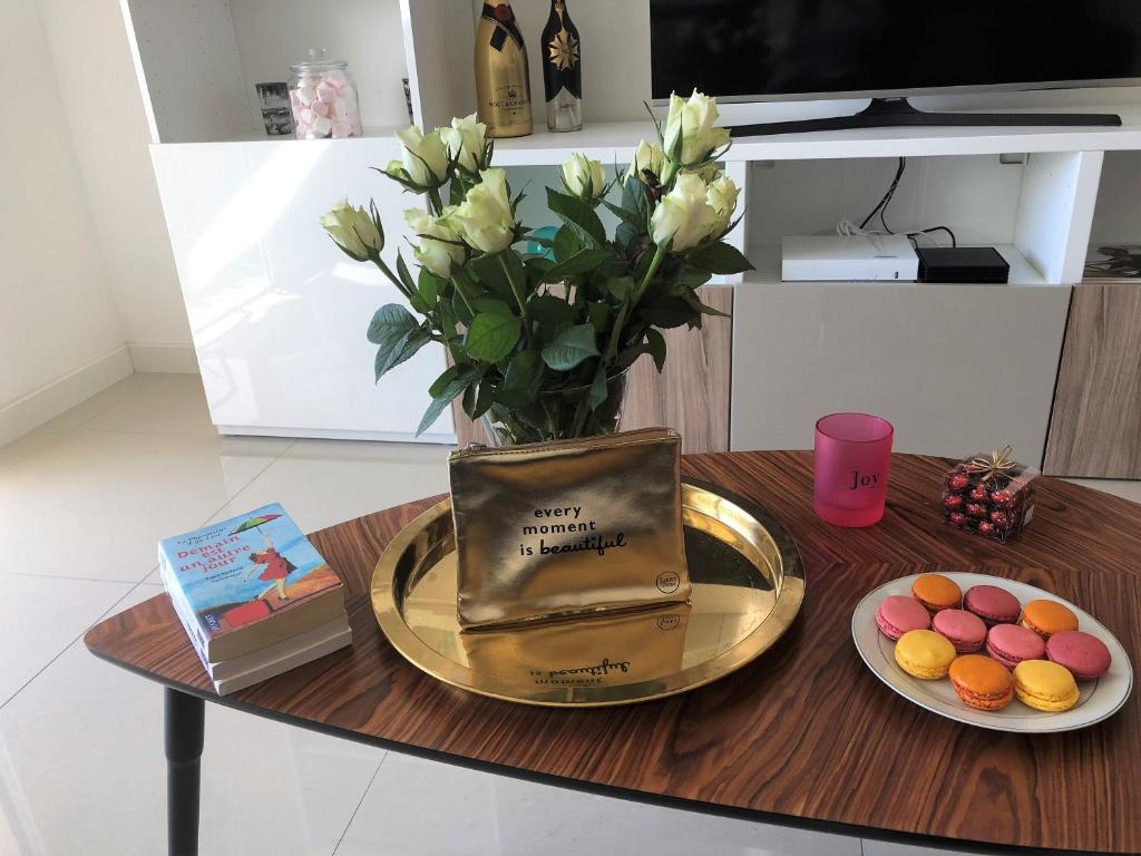 a vase of flowers on a table with a plate of cookies at Appartement Cosy Calme Central-Terrasse Proche Palais in Cannes