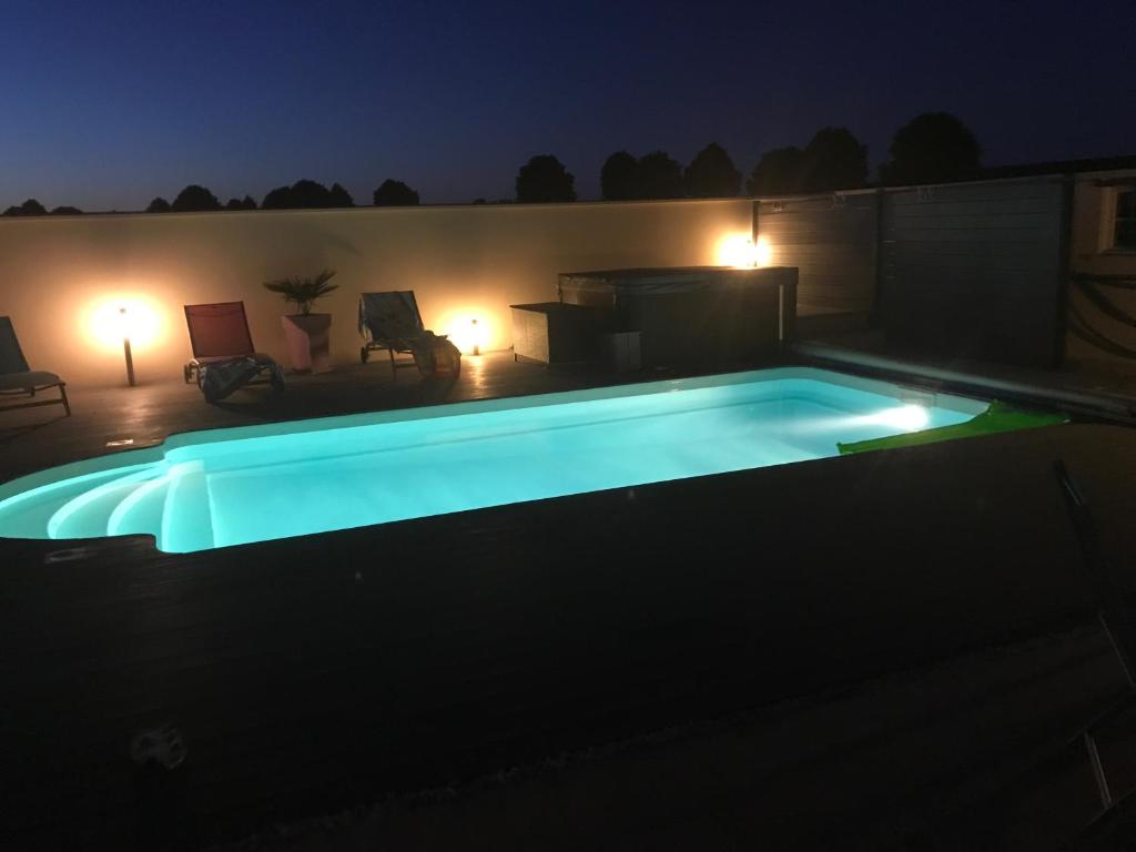 una piscina iluminada por la noche en Chez Jojo & Cassi en Vert-Saint-Denis