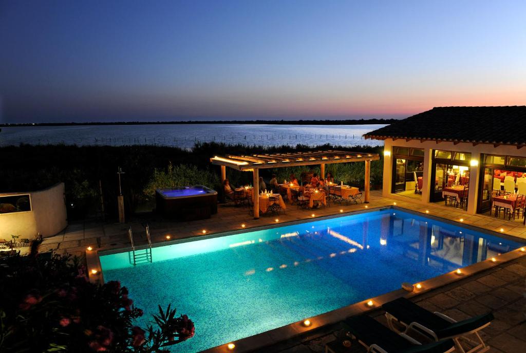 - une piscine en face d'une maison la nuit dans l'établissement Maison l'Etrier, à Saintes-Maries-de-la-Mer