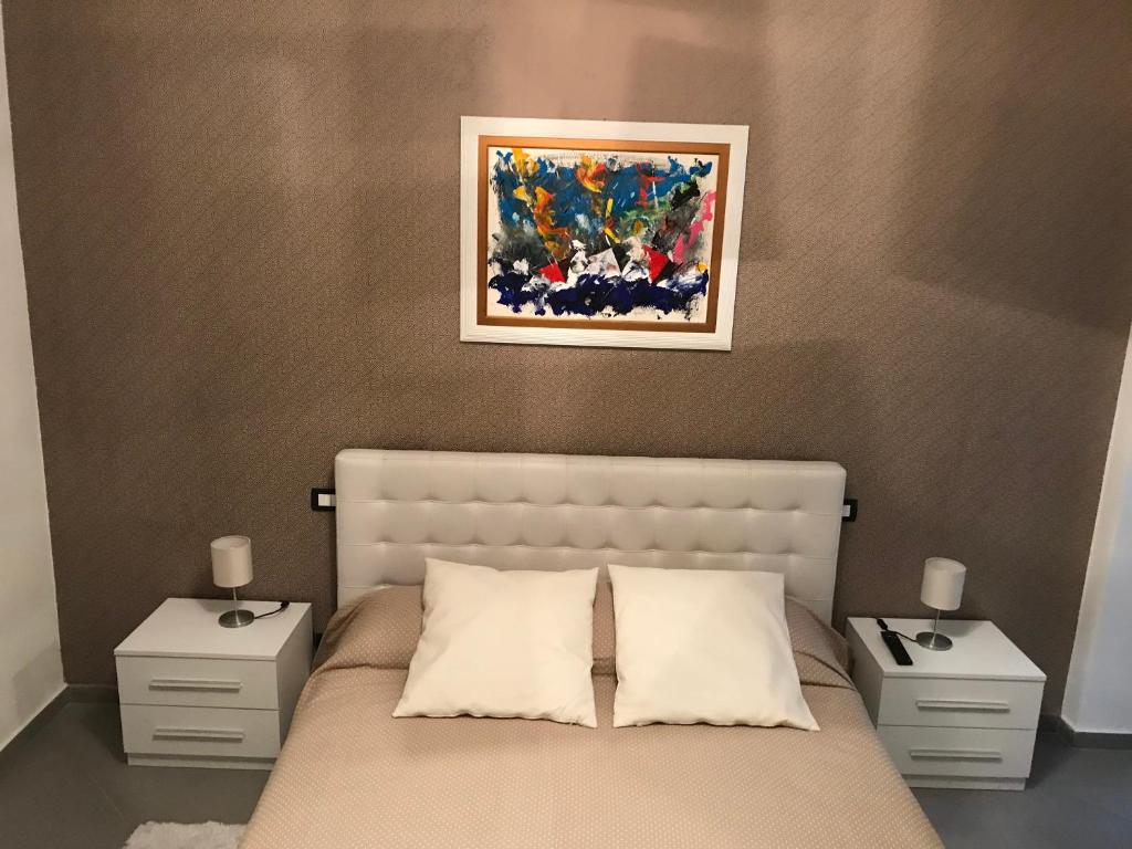 1 dormitorio con 1 cama con 2 mesitas de noche y una pintura en B&B Ricci en Livorno