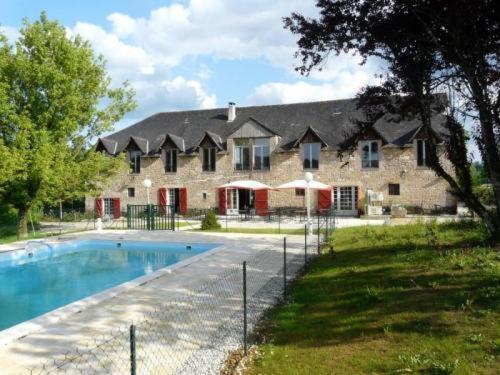 una casa grande con piscina frente a ella en Auberge de Cartassac, en Sarrazac