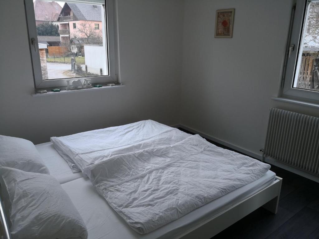 an unmade bed in a bedroom with two windows at FeWo Tanja in Lindau