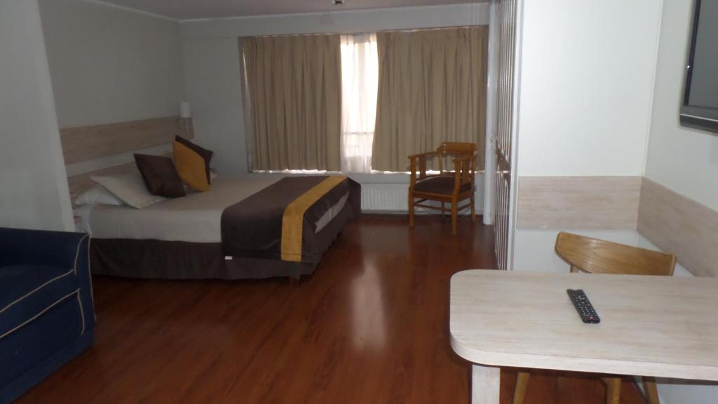 um quarto de hotel com uma cama e uma mesa em Luigi's Apart Hotel em Santiago