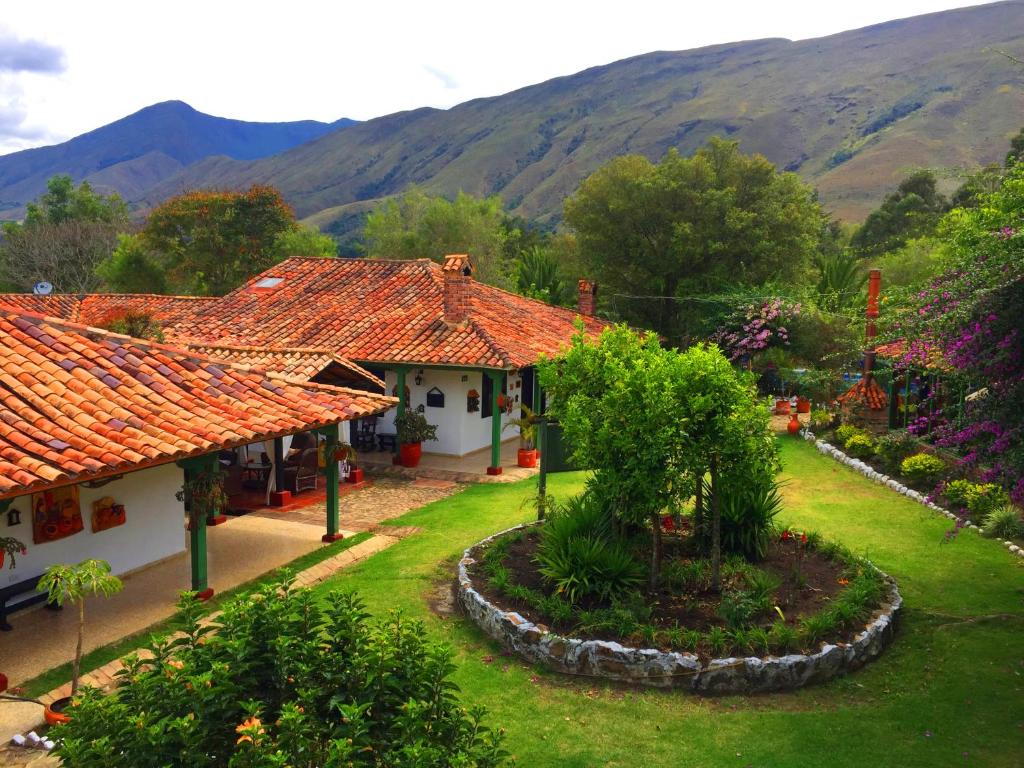 una casa con jardín y montañas en el fondo en Hotel Boutique Iguaque Campestre Spa & Ecolodge, en Villa de Leyva