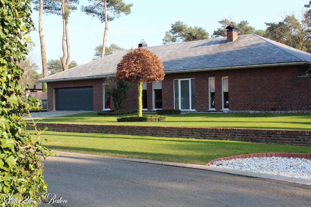 een stenen huis met een boom in de voortuin bij villa 2be in Balen