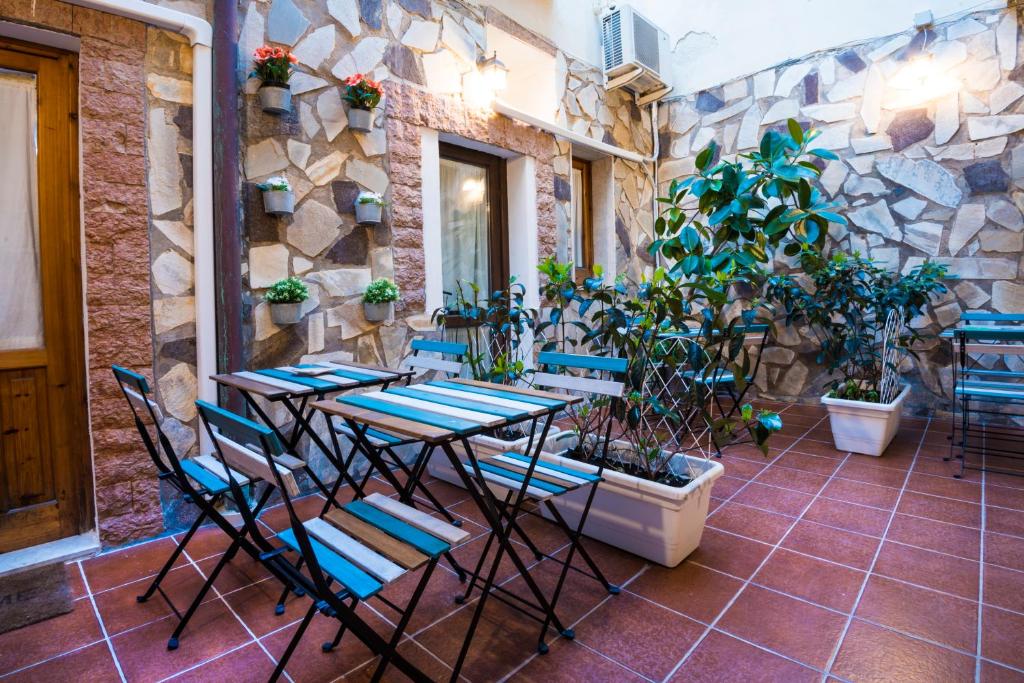 eine Terrasse mit Tischen und Stühlen und einer Steinmauer in der Unterkunft Il Cortiletto di Ortigia in Syrakus