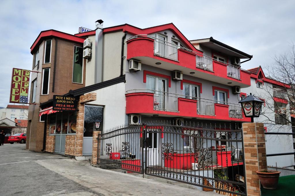 a red and white building with a black fence at Motel Edem in Mostar