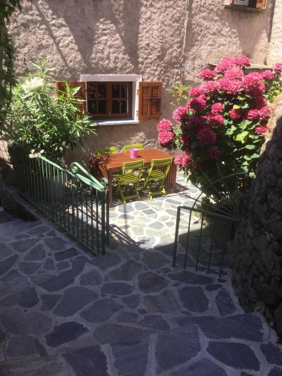 a patio with a table and chairs and flowers at Casa a Stretta in Castello-di-Rostino