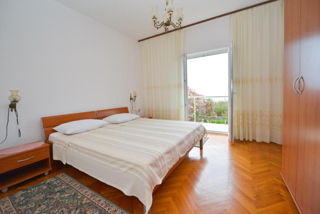 een slaapkamer met een groot bed en een groot raam bij Apartman Nikodem in Novalja