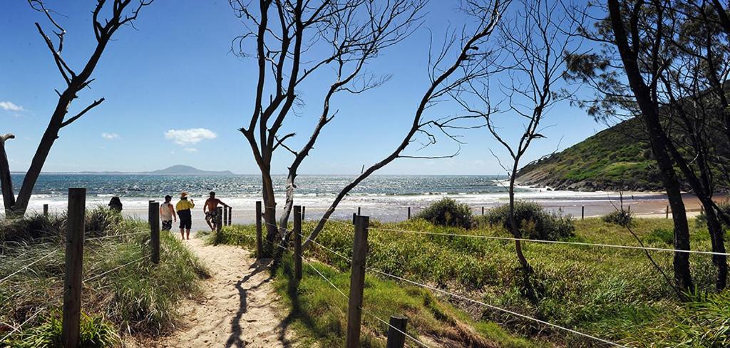 two people walking down a path near the beach at Hat Head Holiday Park in Hat Head