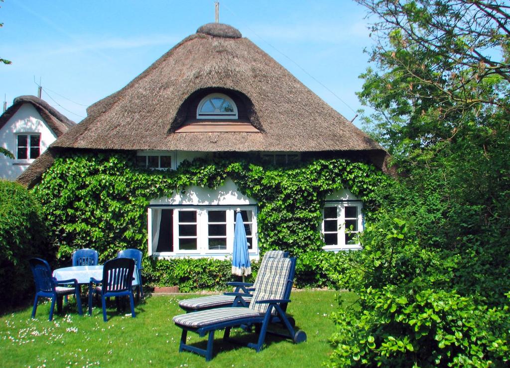 a house with a thatched roof with chairs and a table at Föhrer Friesenkate Ost in Nieblum