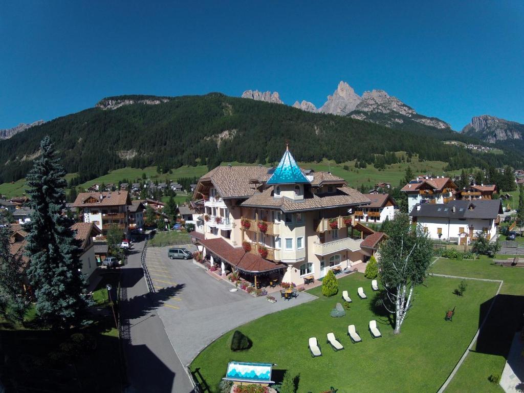 a large building with a blue roof in front of a mountain at Hotel Chalet Sas Morin in Pozza di Fassa