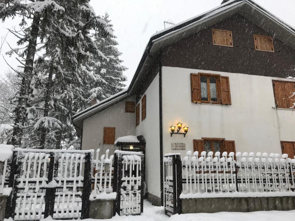 una casa blanca con una cerca en la nieve en Villa delle tre lanterne, en Roccaraso