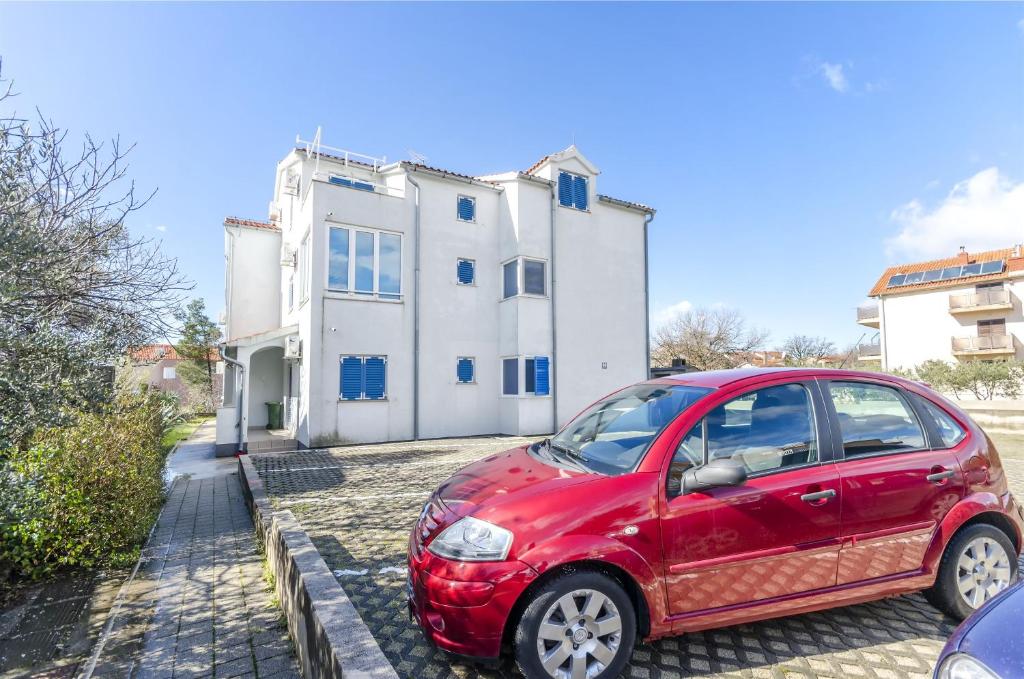 a red car parked in front of a house at Apartment Branka in Srima