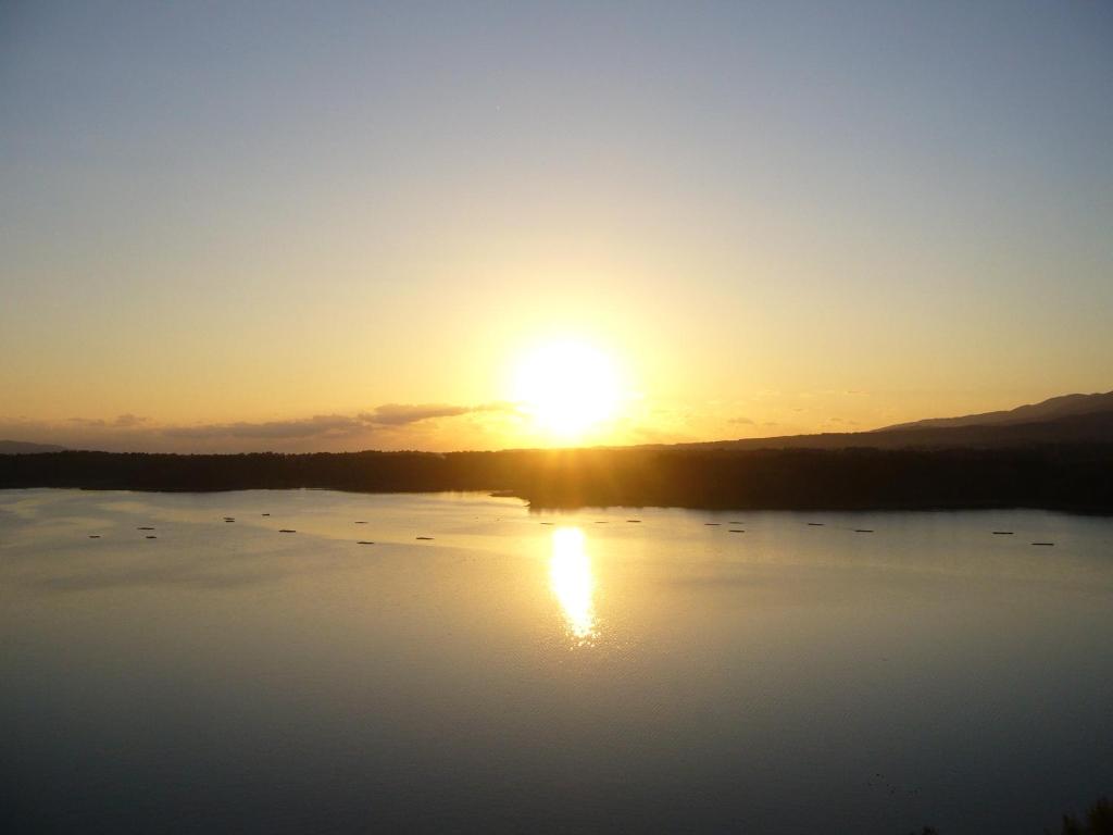 zachód słońca nad jeziorem z ptakami na wodzie w obiekcie Aokiya w mieście Sado
