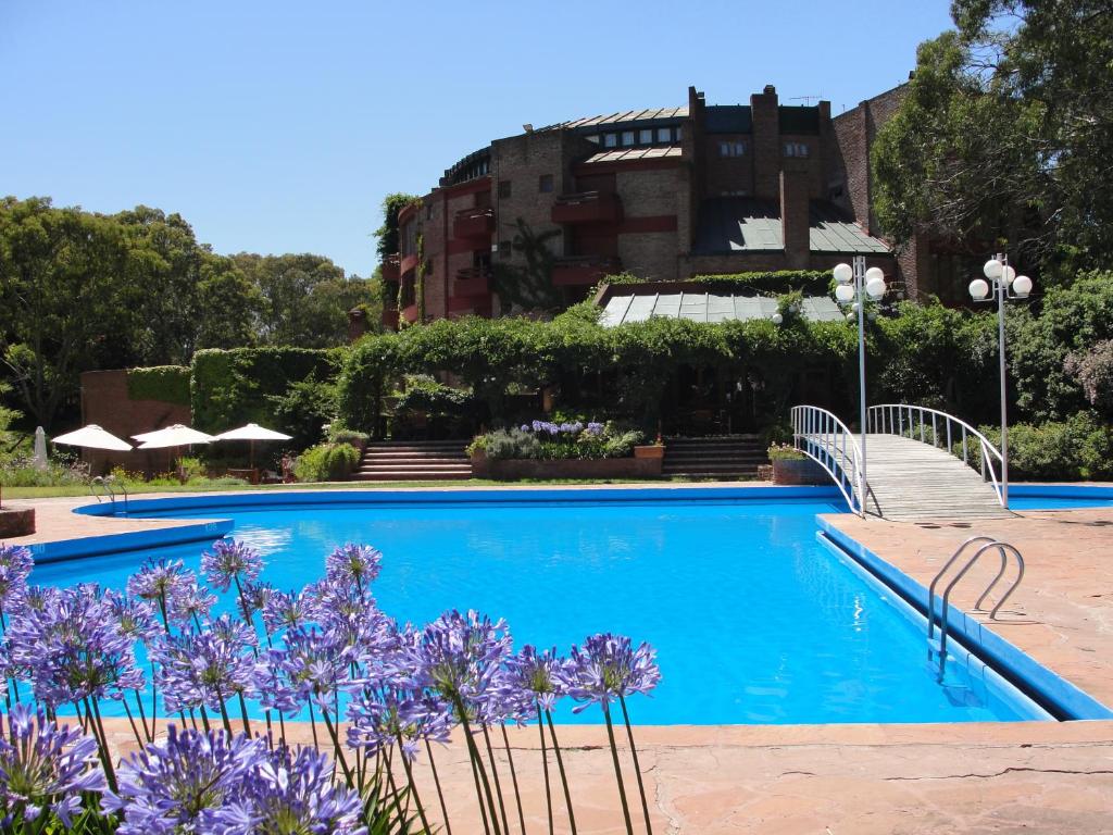 a swimming pool with purple flowers in front of a building at Hotel del Bosque in Pinamar
