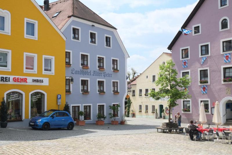 a blue car parked in front of colorful buildings at Landhotel Alter Peter in Kipfenberg