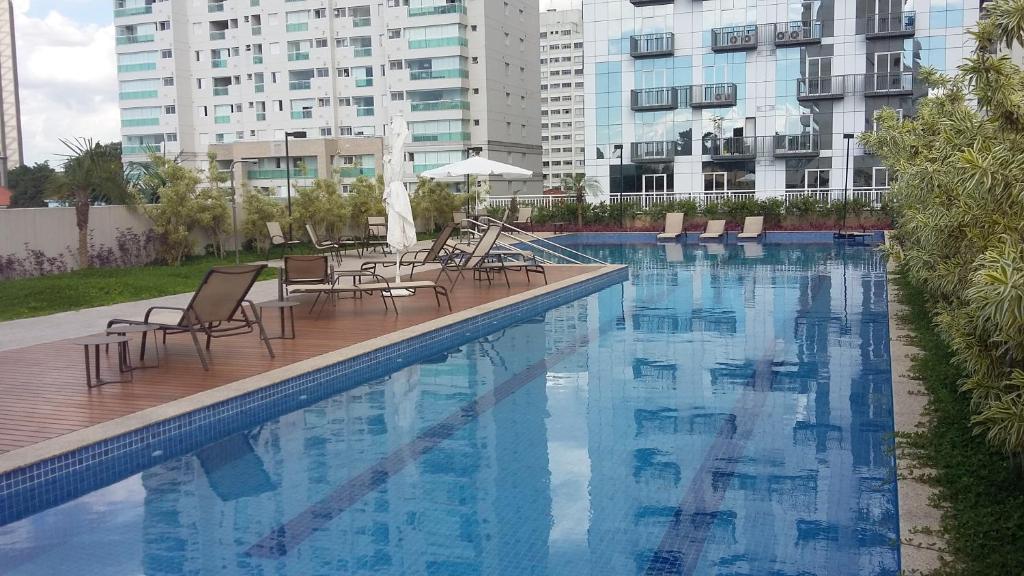 een zwembad met stoelen, tafels en gebouwen bij Now Alto Da Boa Vista in Sao Paulo