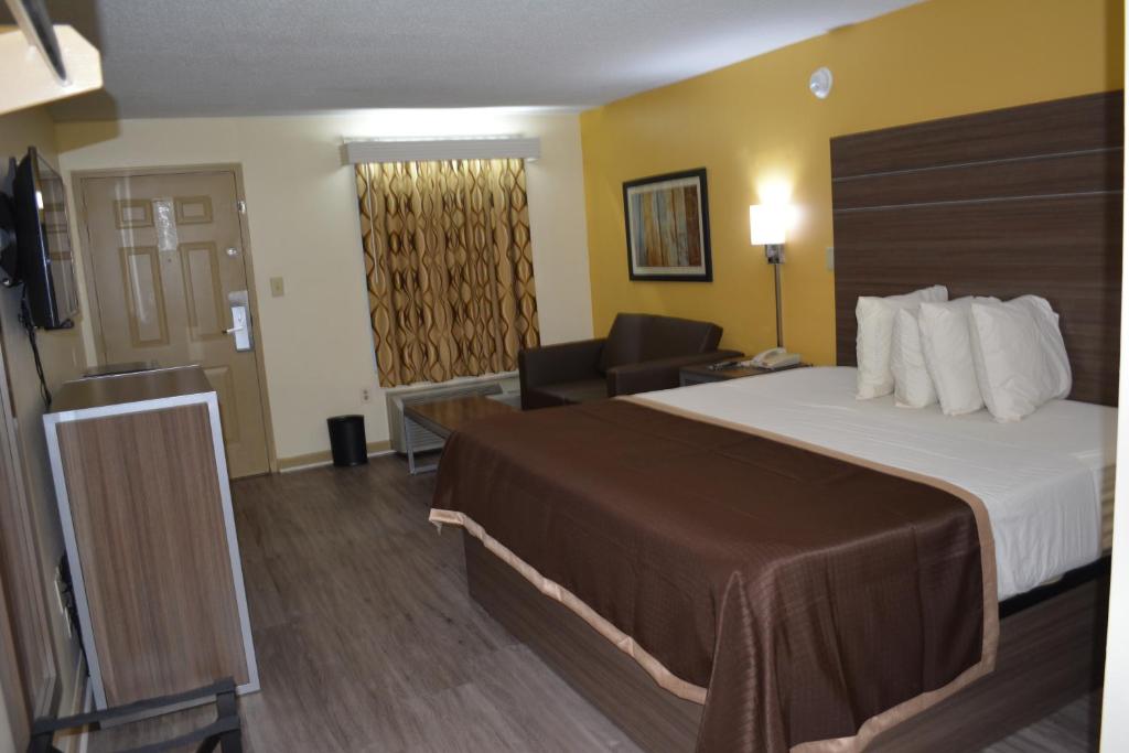 a hotel room with a bed and a television at Southern Inn Lumberton in Lumberton