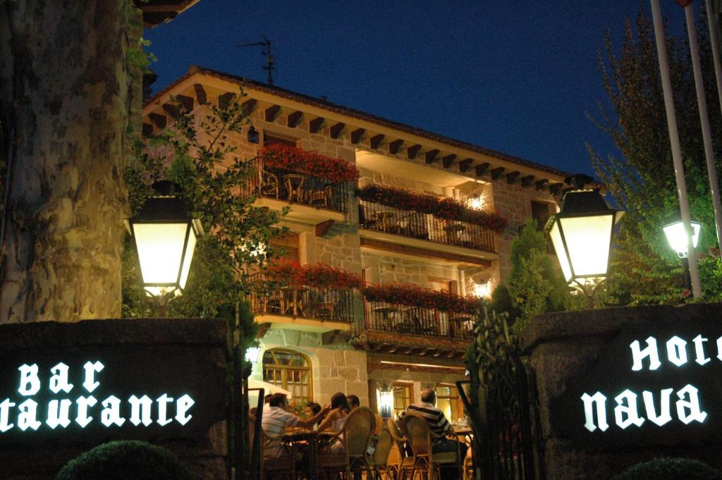 a building with people sitting outside of it at night at Nava Real in Navacerrada