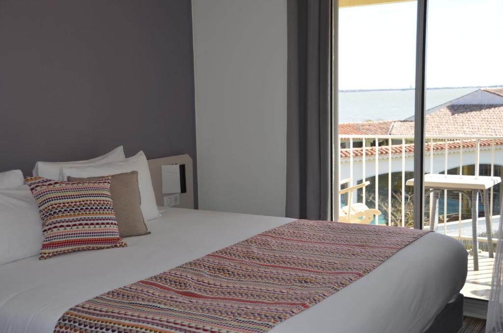 a bedroom with a bed with a view of a balcony at Hotel et Spa Les Cleunes Oléron in Saint-Trojan-les-Bains
