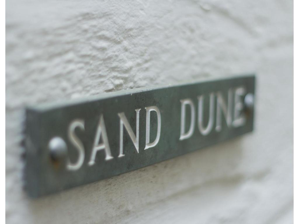a street sign for sand dune on a building at Sand Dune in Looe