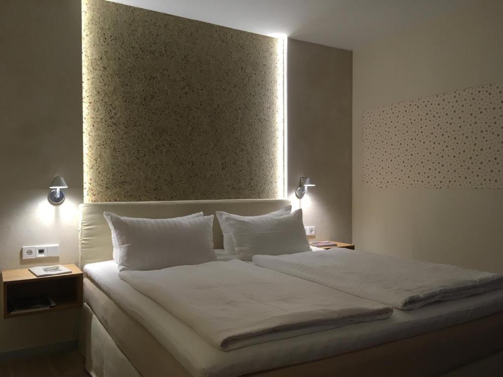 1 dormitorio con 1 cama grande con sábanas y almohadas blancas en Landhotel Broda, en Neubrandenburg