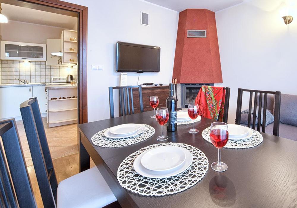 stół jadalny z dwoma kieliszkami czerwonego wina w obiekcie VisitZakopane - Paris Apartment w Zakopanem