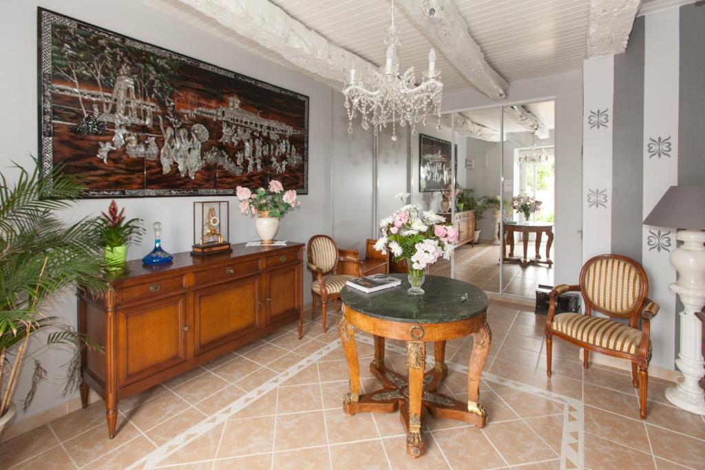 sala de estar con mesa y sillas en Chambres d'hôtes - Les Palmiers, en Corseul