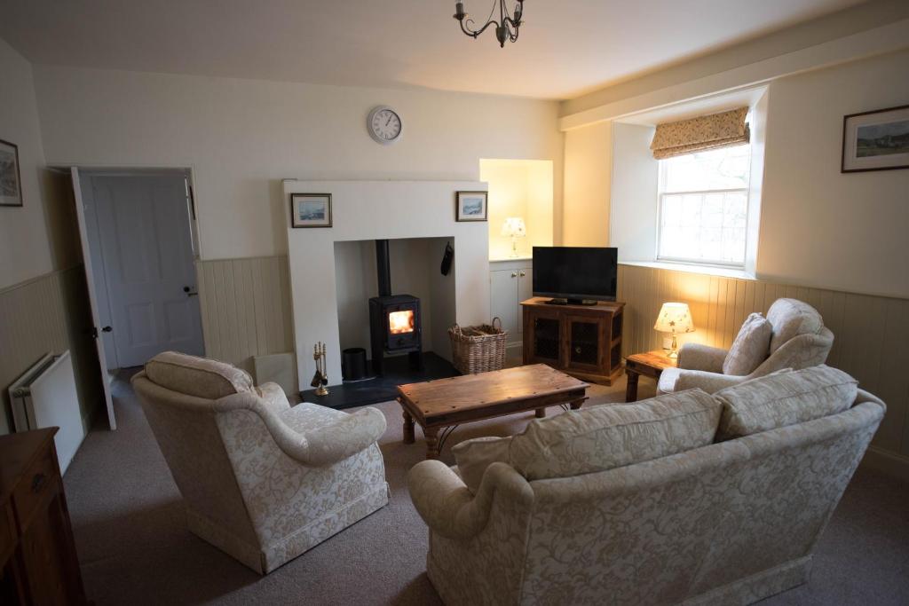 a living room with two chairs and a table and a television at Elibank House Apartment in Walkerburn