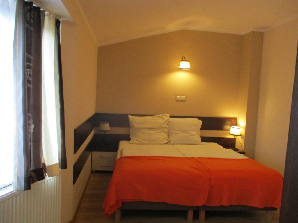 sypialnia z łóżkiem z pomarańczowym kocem w obiekcie Hotel Pod Platanami w mieście Trzebnica