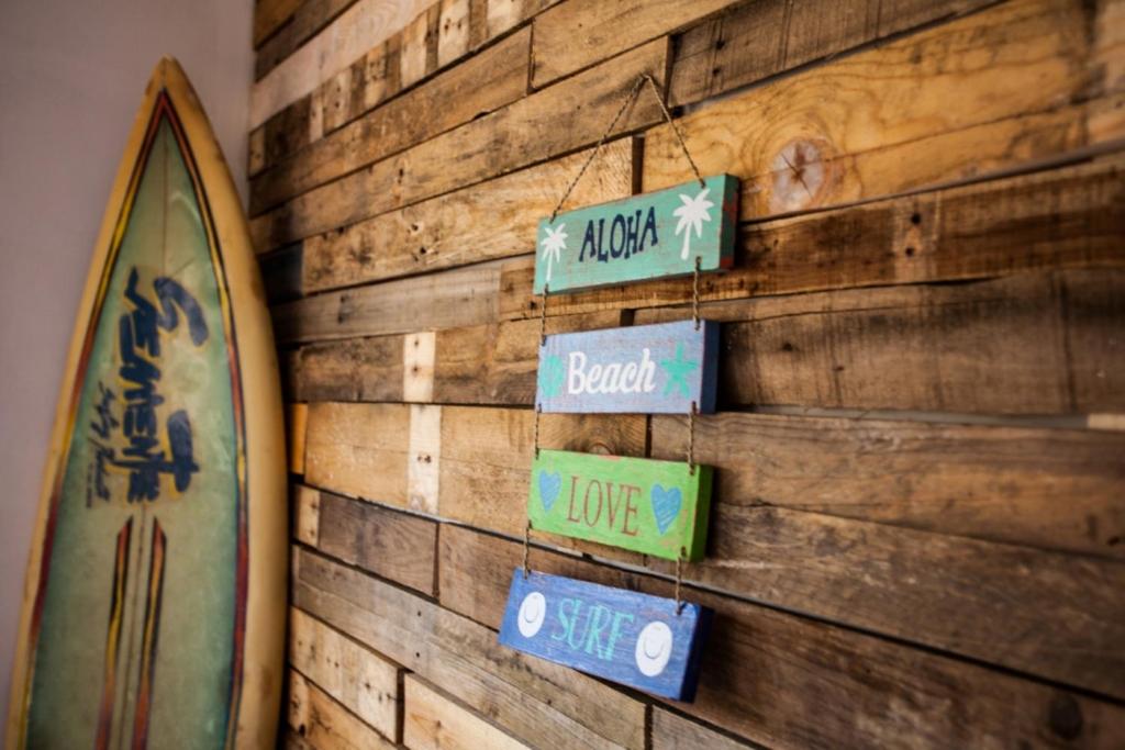 een houten muur met borden en een surfplank bij Lisbon Surf Villa in Costa da Caparica