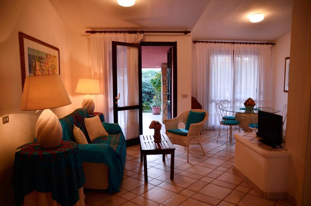 a living room with a green couch and chairs at Villa Flamingo in Villasimius