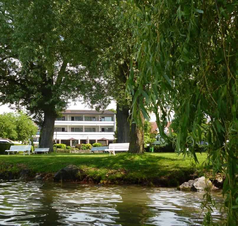ein Gebäude im Hintergrund mit einem Fluss und Bäumen in der Unterkunft Hotel Seepark Garni in Überlingen