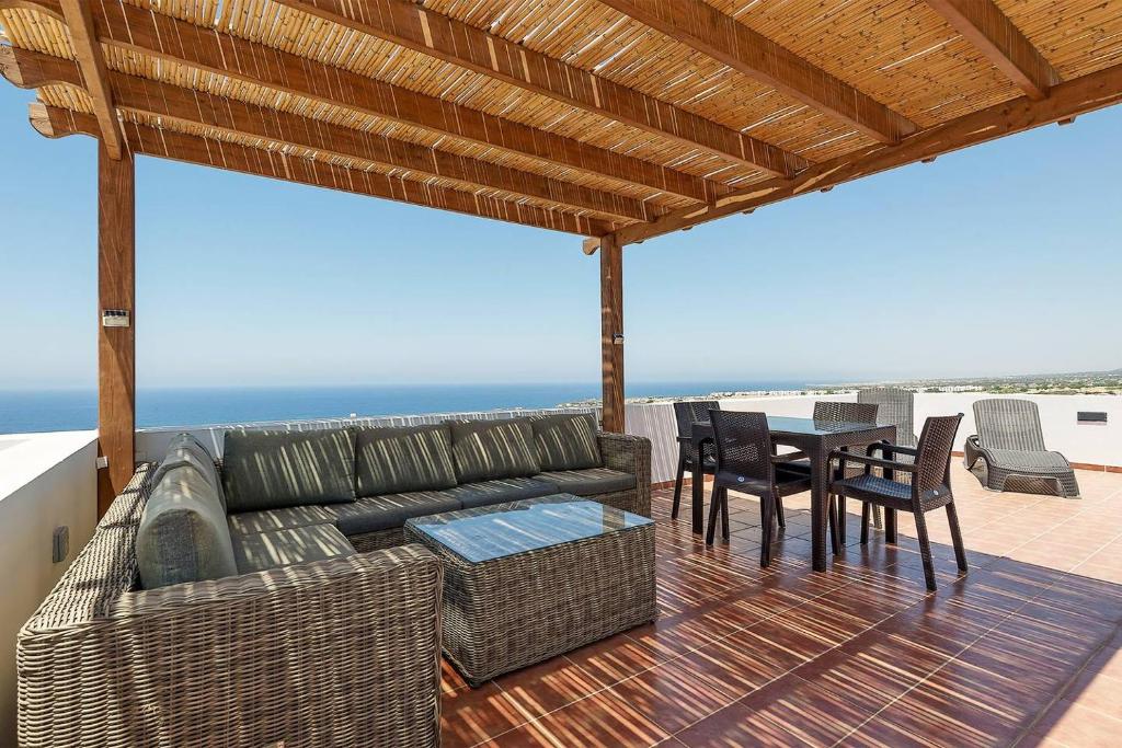 a patio with a couch and a table and chairs at Joya Cyprus Mermaid Penthouse Apartment in Saint Amvrosios