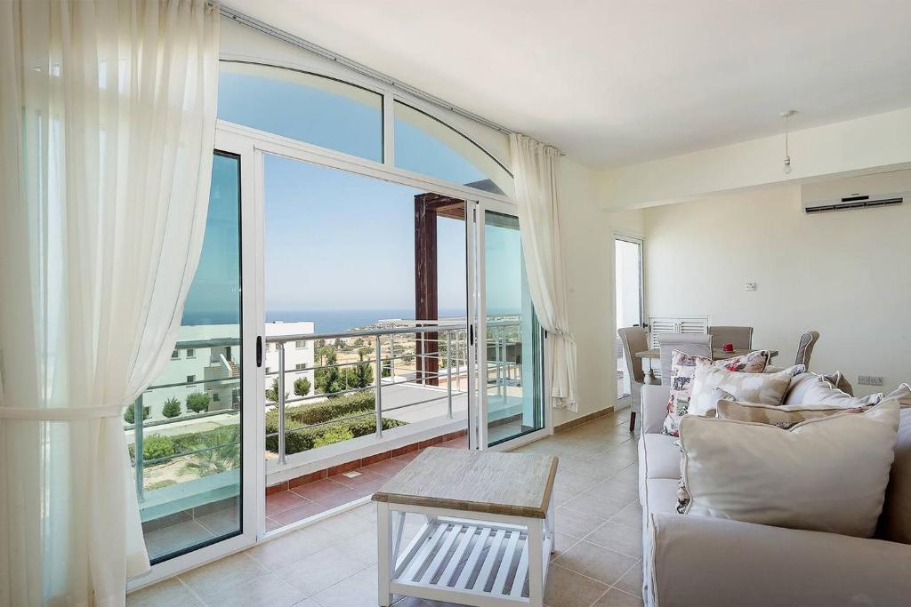 a living room with a couch and a large window at Joya Cyprus Mandalay Penthouse Apartment in Saint Amvrosios