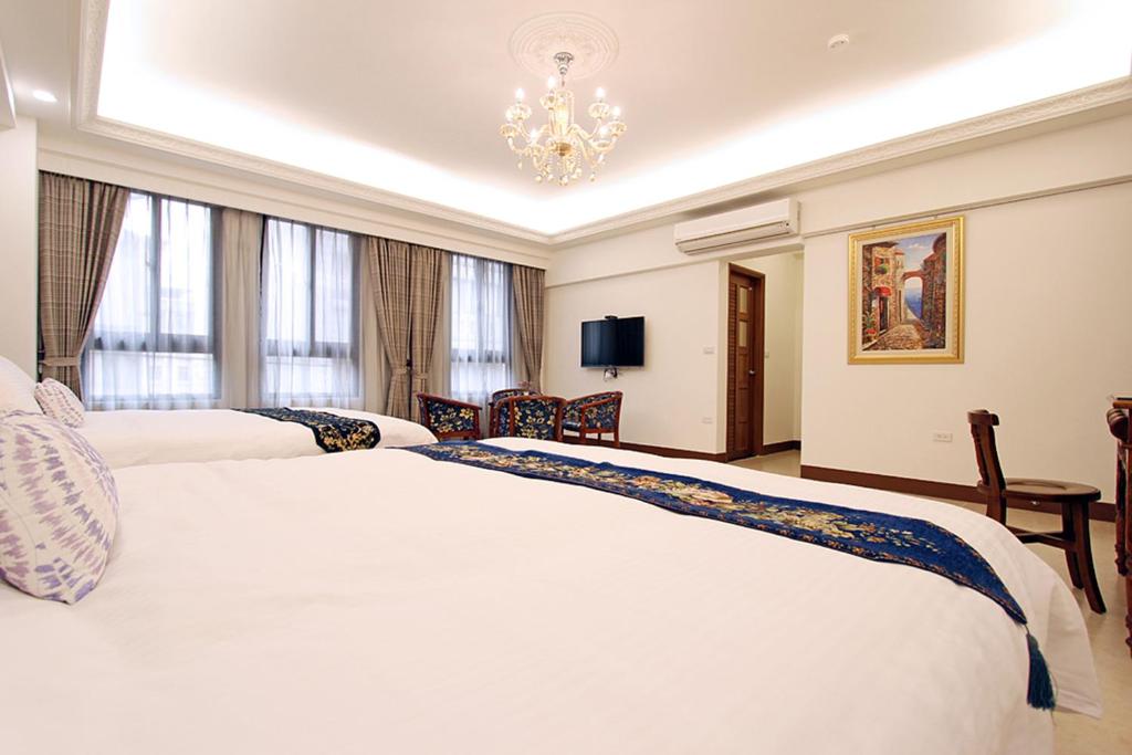 花蓮市にあるTuscany Homestayのベッド2台とシャンデリアが備わるホテルルームです。