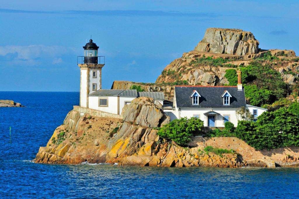 un faro en una isla rocosa en el agua en Goélia Résidence du Golf de l'Océan en Carantec