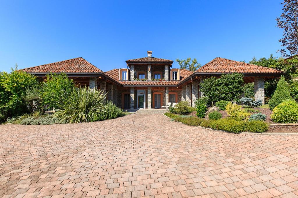 une grande maison avec une allée en briques en face de celle-ci dans l'établissement Villa Il Grotto, à Verbania