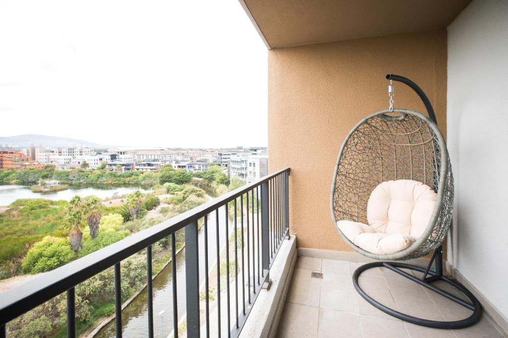 una silla de mimbre colgante en un balcón con vistas en Waters Edge Self-Catering Apartment, en Ciudad del Cabo