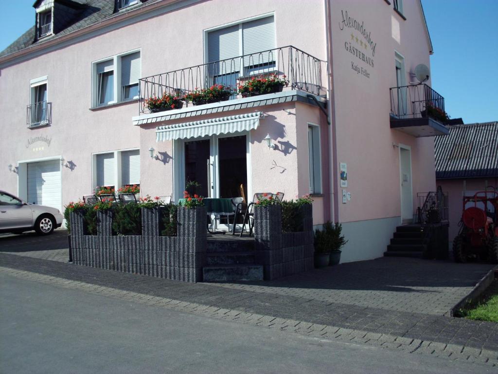 ein rosafarbenes Gebäude mit einem Balkon mit Blumen darauf in der Unterkunft Gästehaus Alexanderhof in Leiwen