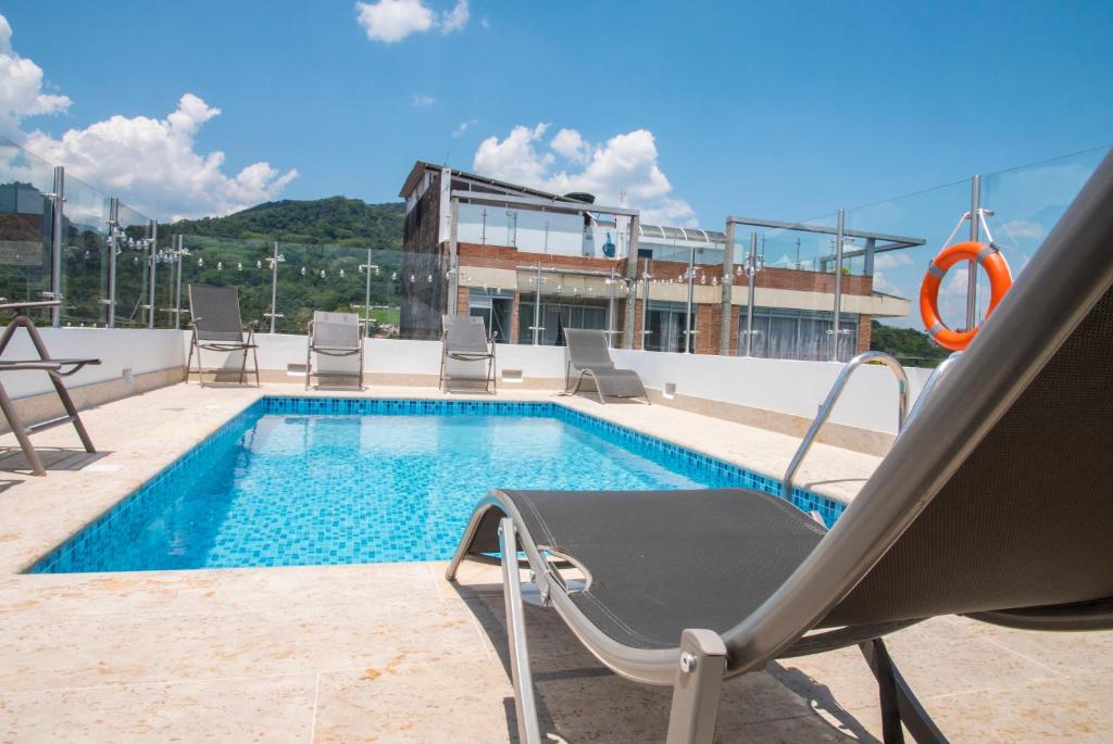 - une piscine avec des chaises et un fauteuil inclinable à côté d'un bâtiment dans l'établissement Hotel Grand H&R, à Villeta