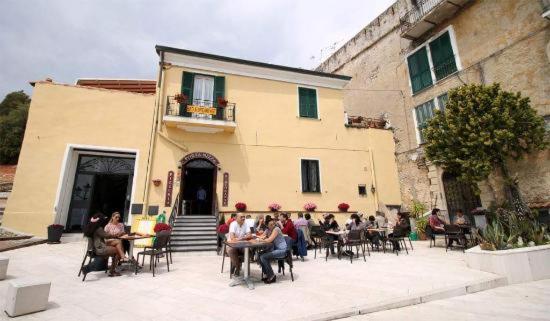un gruppo di persone seduti ai tavoli fuori da un edificio di appartamento rocchetta a Ventimiglia